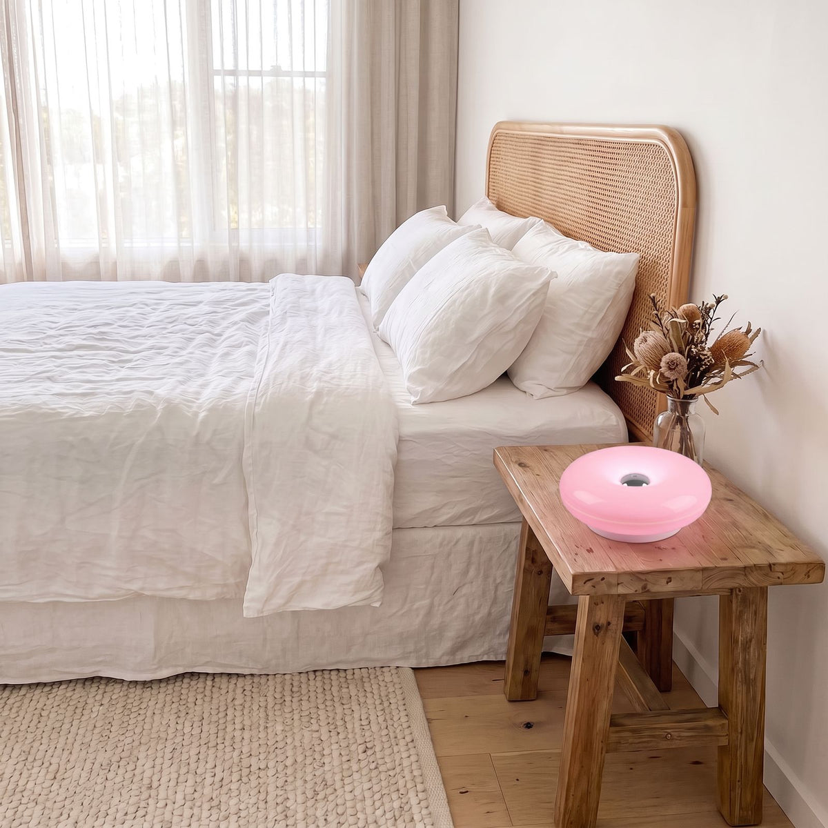 Pink acrylic donut lamp on a timber bedside table in a coastal bedroom