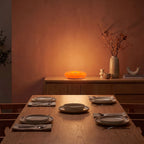 Orange acrylic donut lamp on a sideboard in a dining room at night