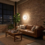 White acrylic donut lamp hung on a brick wall beside a sofa in a loft living room at night