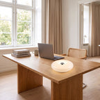 White acrylic donut lamp lying flat on an oak desk in a bright home office