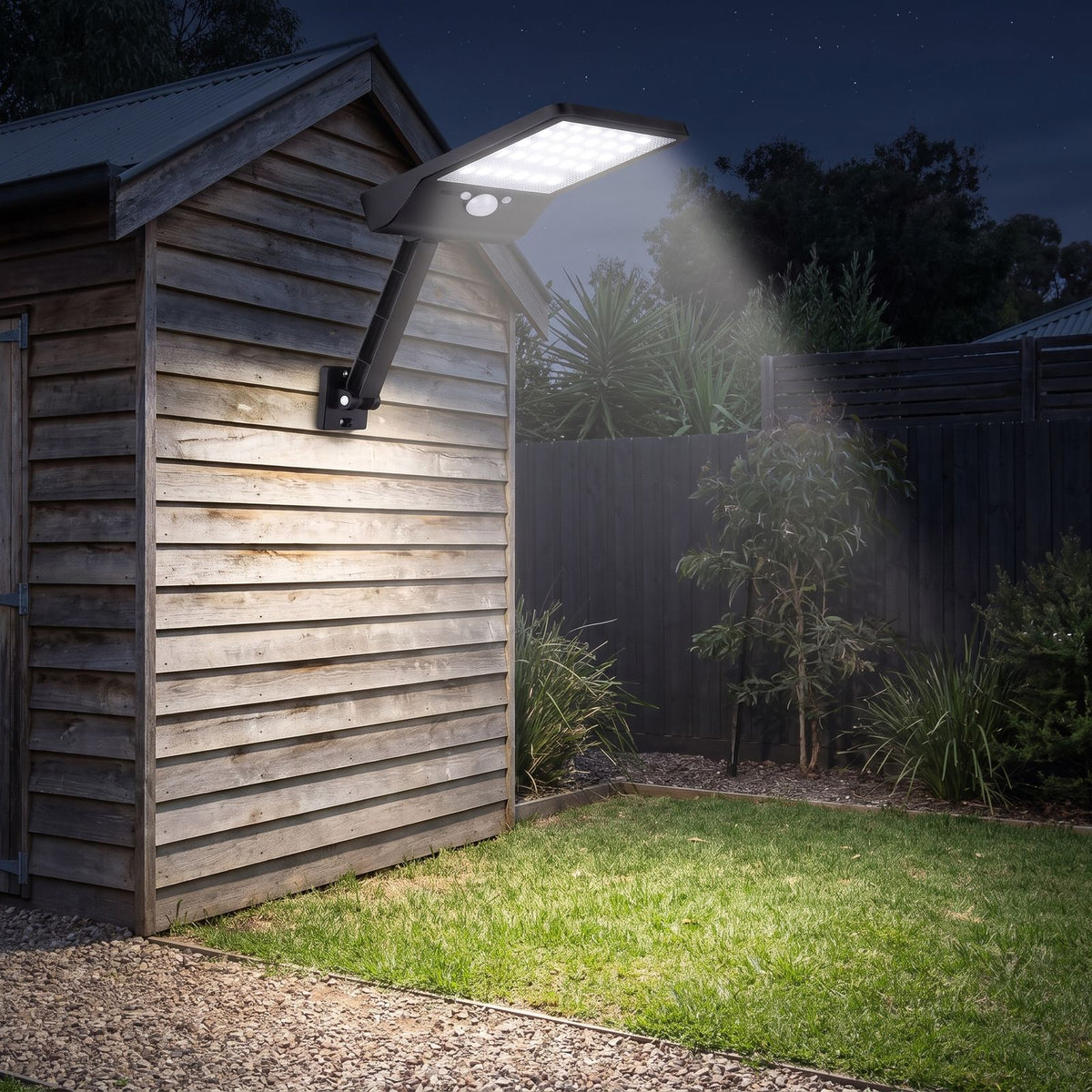 Solar sensor wall light on an adjustable arm on a garden shed wall at night