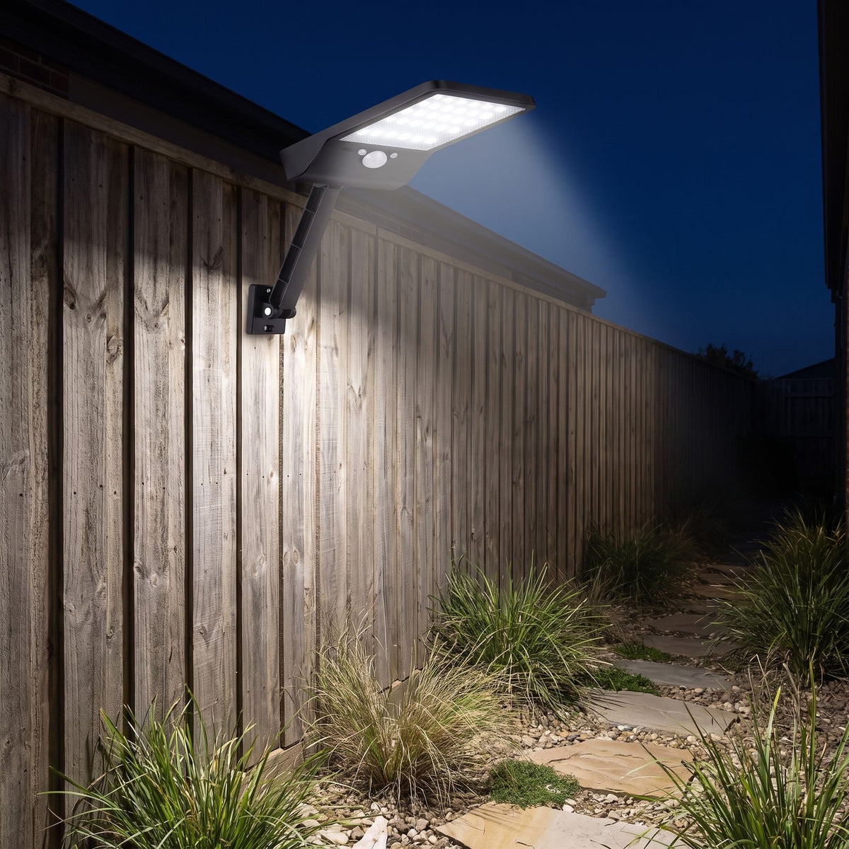 Solar sensor wall light on an adjustable arm on a timber fence along a side path