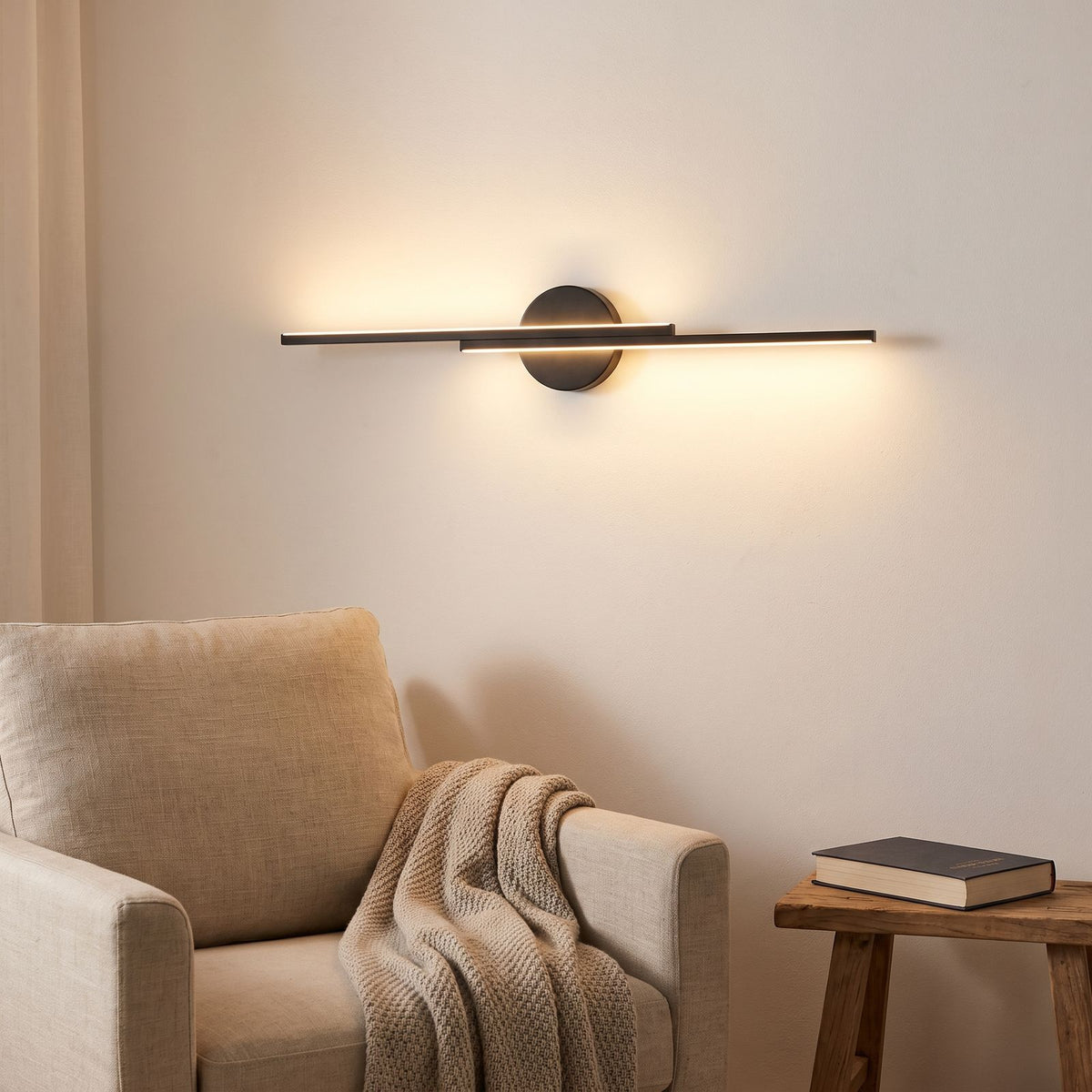 Bar and disc LED wall sconce above an armchair in a reading corner