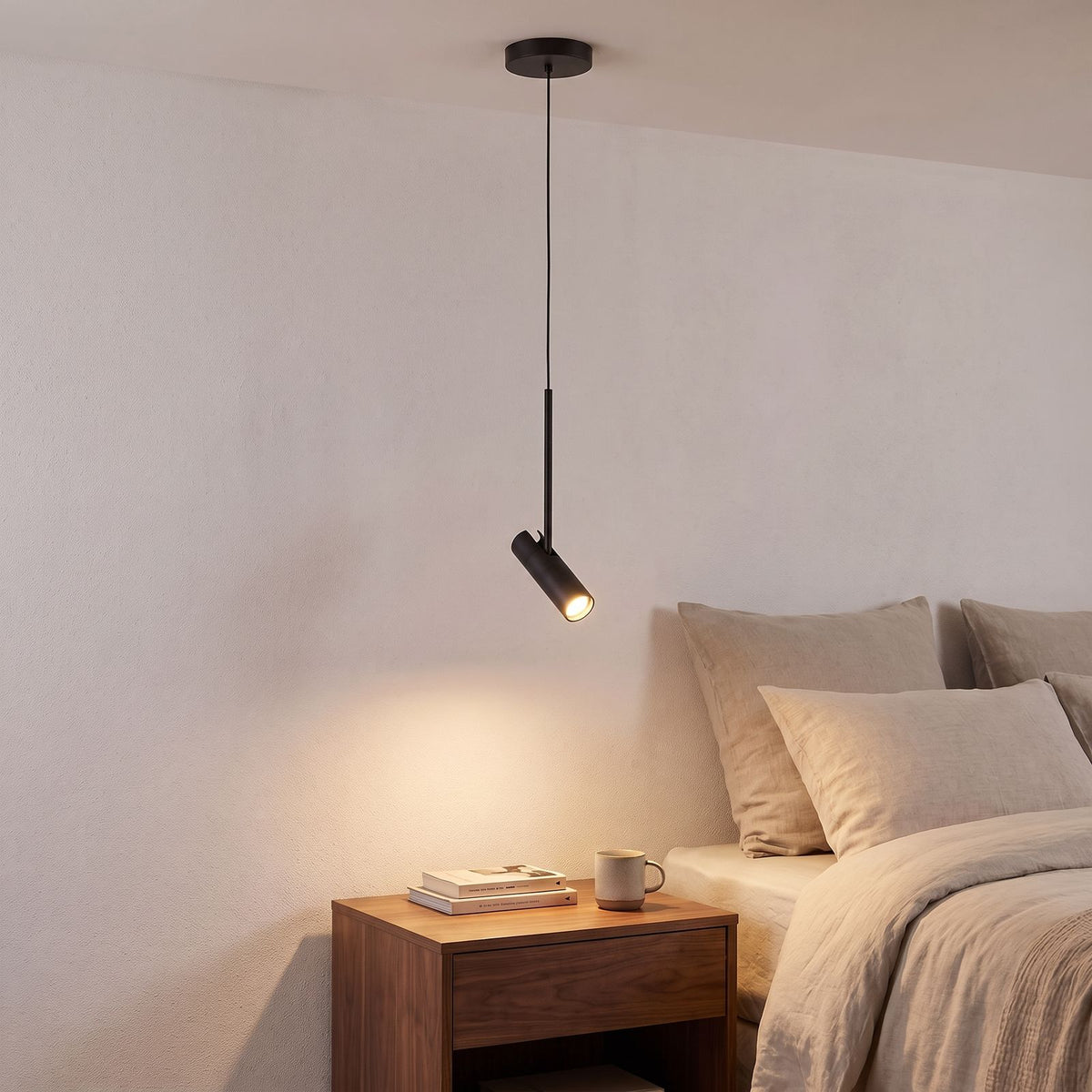 Adjustable Black Metal Cylinder Spotlight Pendant Light over a bedside table