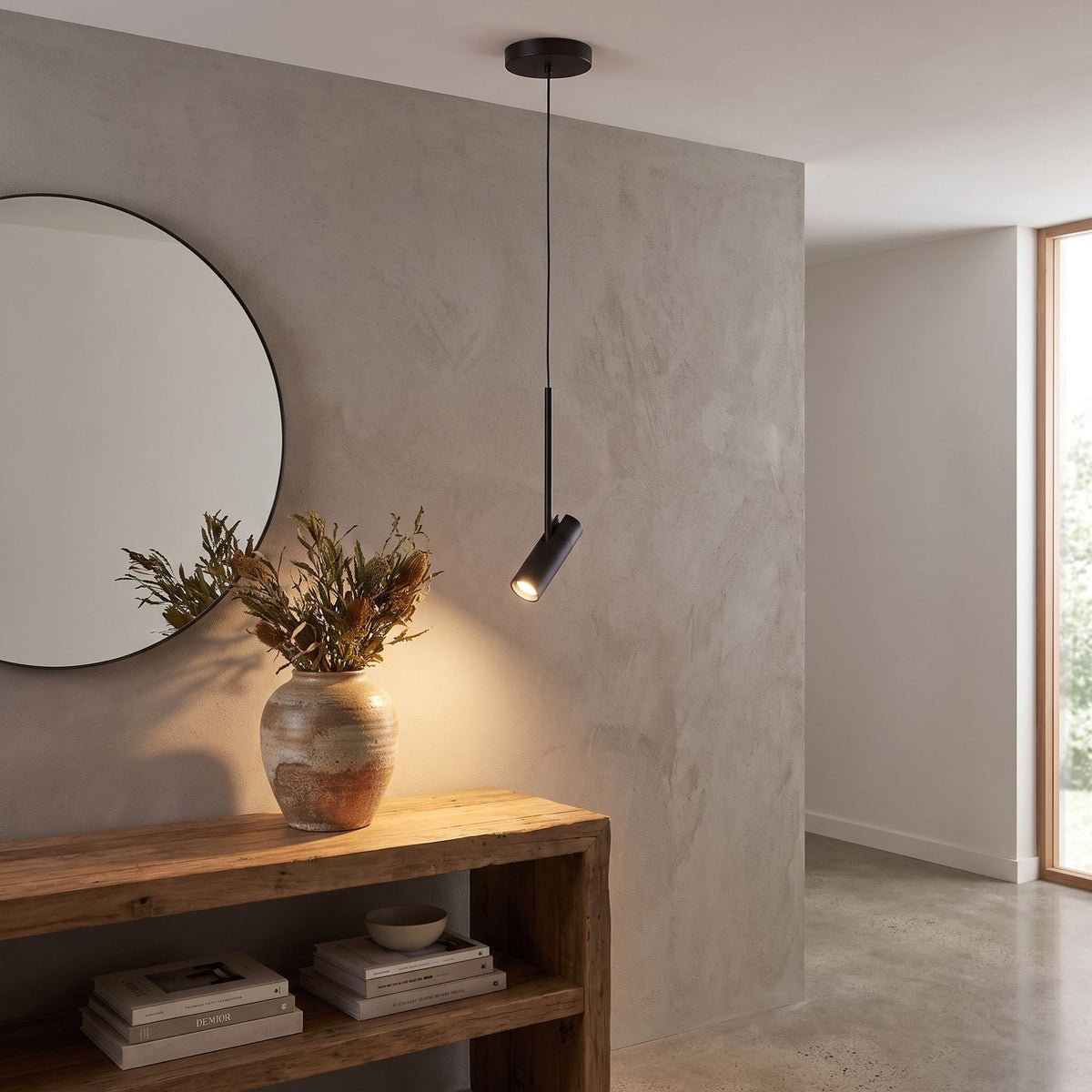 Black cylinder spotlight pendant light above an entry hall console