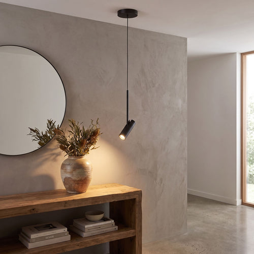 Black cylinder spotlight pendant light above an entry hall console