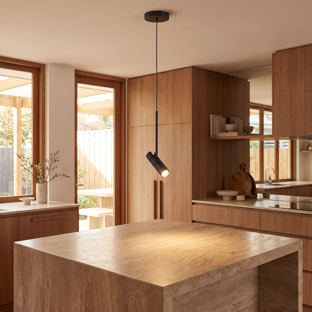 Black cylinder spotlight pendant light over a kitchen island bench