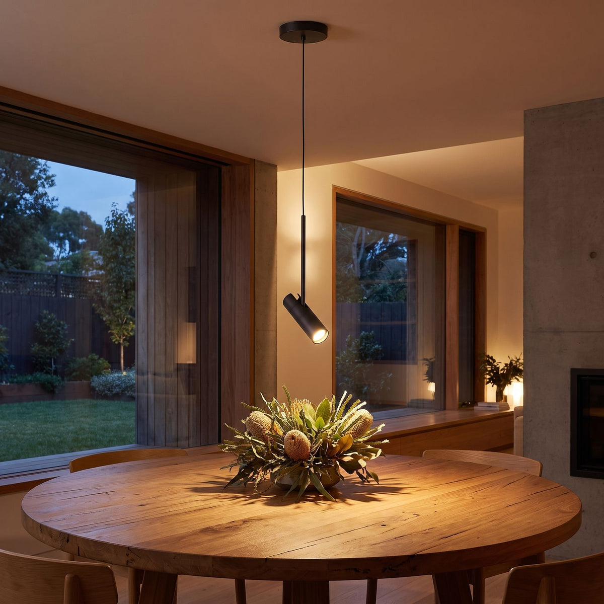 Black cylinder spotlight pendant light above a round dining table