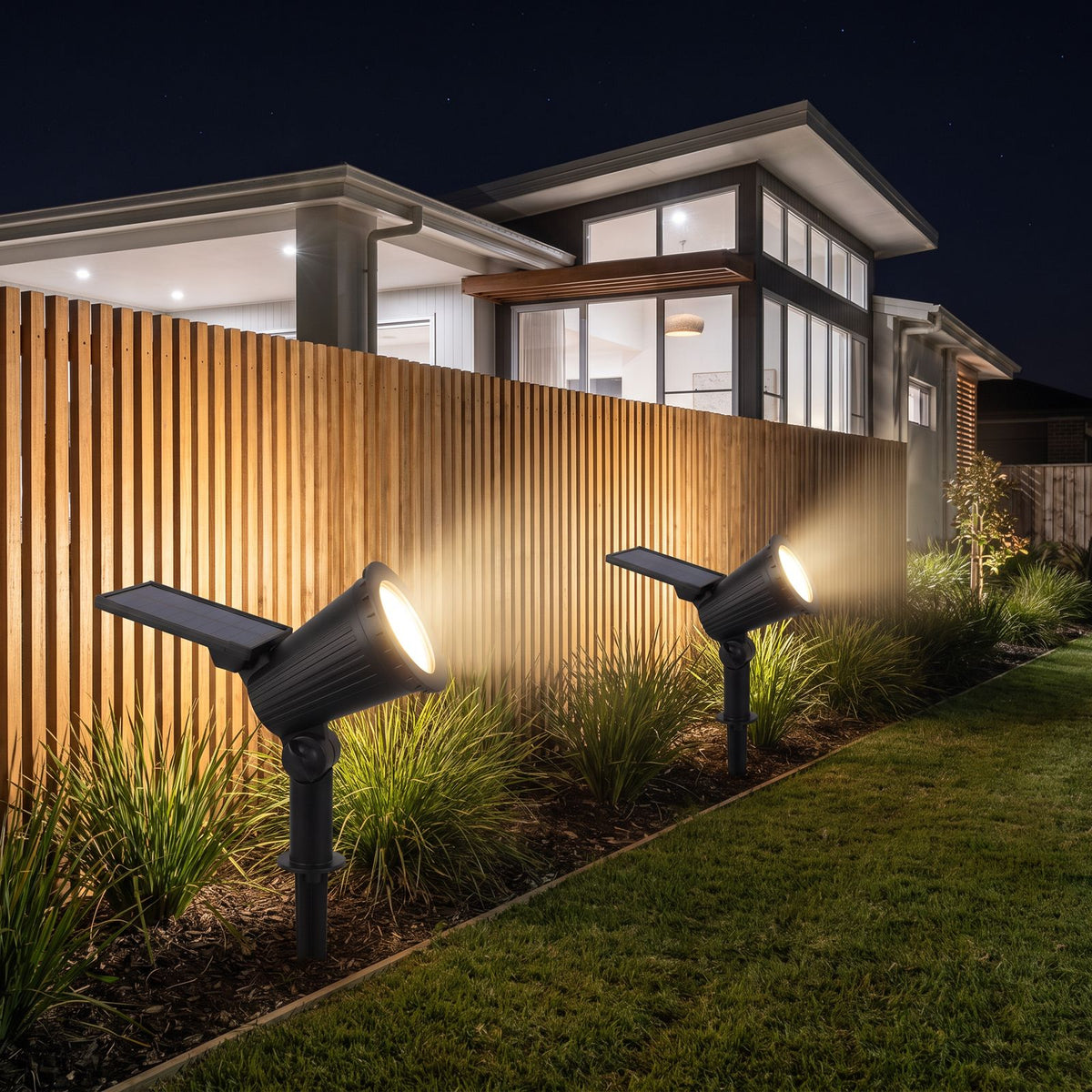 Solar spotlight garden light along a lawn edge and slat fence