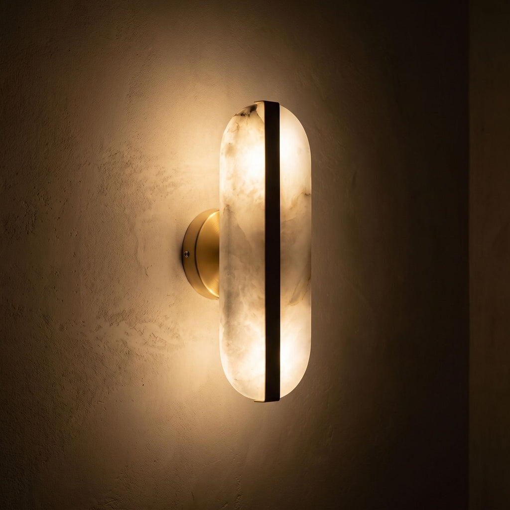 Alabaster and Brass Wall Sconce glowing on a plaster wall at night