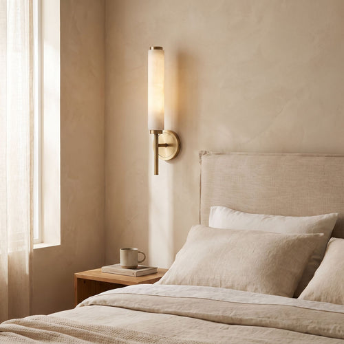Alabaster Candle Brass Wall Sconce on a bedroom wall beside the bed
