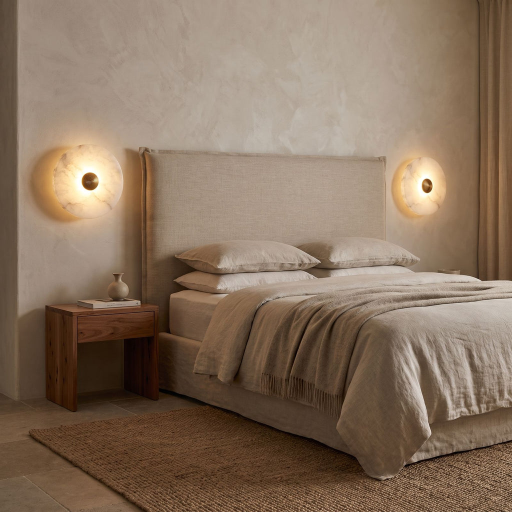 A pair of Alabaster Disc Wall Lights either side of a bed headboard