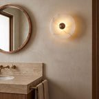 Alabaster Disc Wall Light beside a round mirror in a powder room