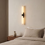 Alabaster Effect Cylinder LED Wall Light in matte black mounted beside a bed in a warm neutral bedroom