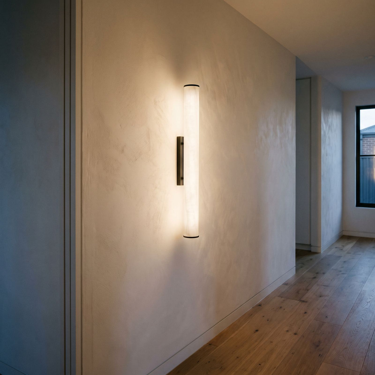 Alabaster Effect Cylinder LED Wall Light lighting a plaster hallway wall in the evening