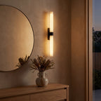 Alabaster effect cylinder wall light beside a round mirror in an entry hall