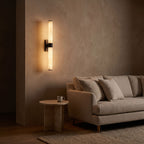 Alabaster Effect Cylinder LED Wall Light on a clay toned living room wall at night