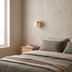 Alabaster Orb Wall Light with Gold Base on a bedroom wall beside the bed