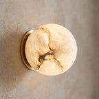 Alabaster Orb Wall Light with Gold Base, close view at 45 degrees on a plaster wall