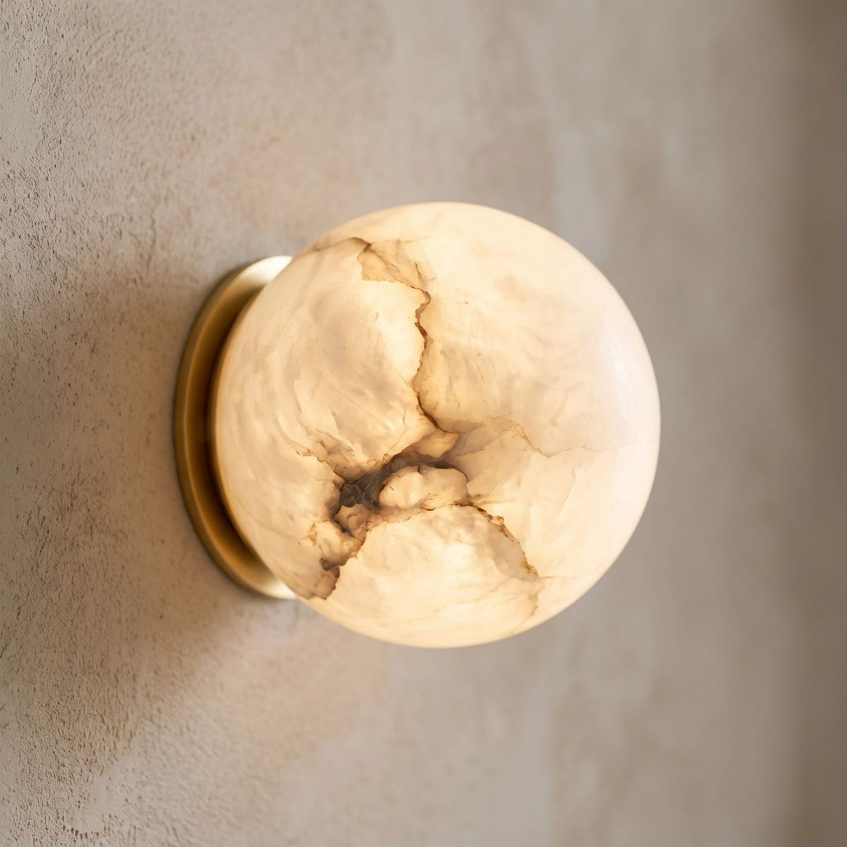 Alabaster Orb Wall Light with Gold Base, close view at 45 degrees on a plaster wall