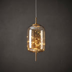 Close view of the amber glass capsule pendant with the starry LED string glowing inside