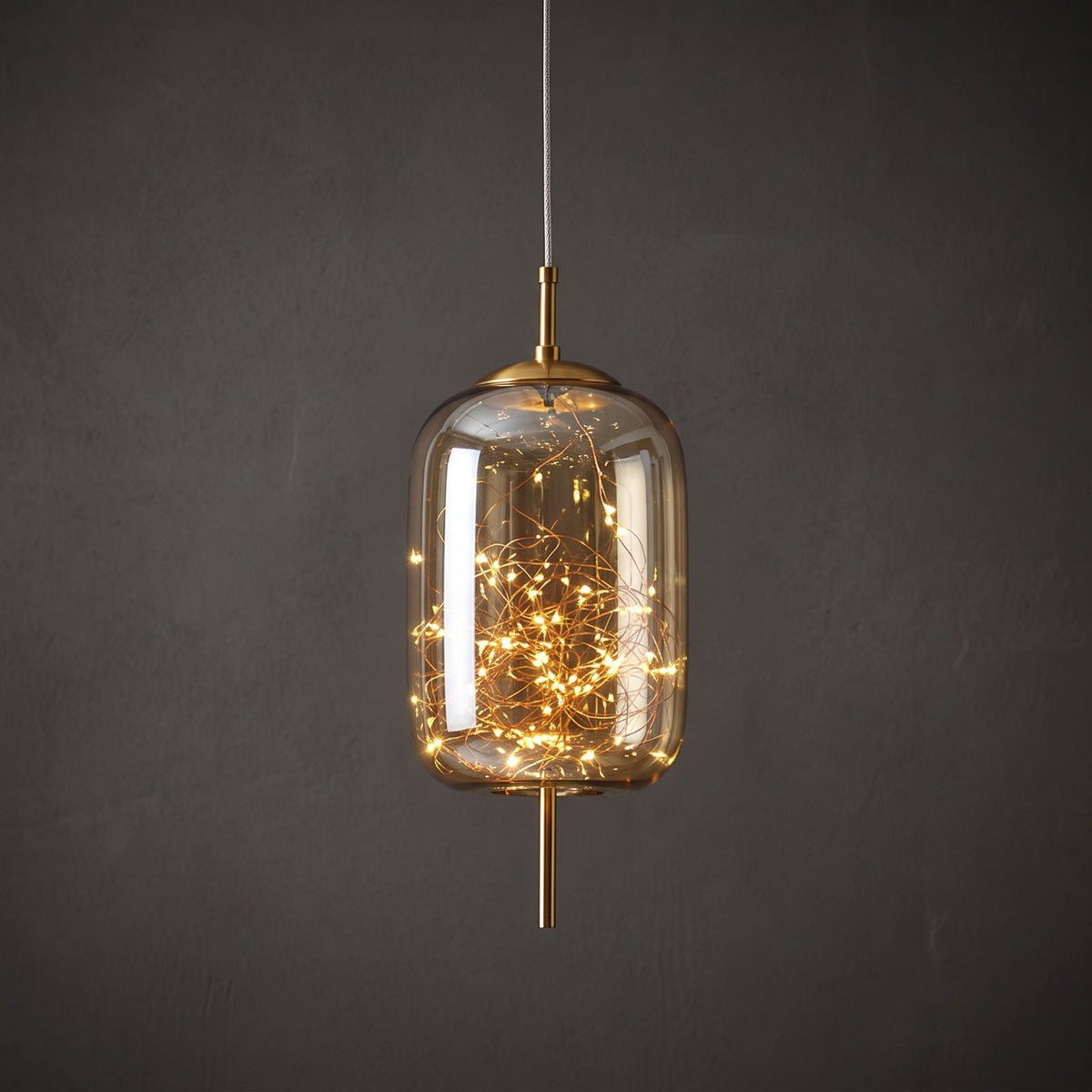 Close view of the amber glass capsule pendant with the starry LED string glowing inside