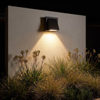 Angled wedge downward outdoor wall light on a garden wall at night