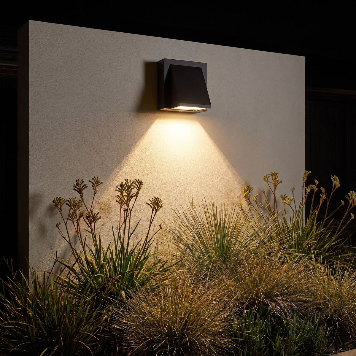 Angled wedge downward outdoor wall light on a garden wall at night