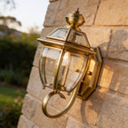 Antique Brass Glass Outdoor Wall Lantern on a sandstone wall, angled close view
