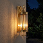 Arabian Style Brass and Glass Outdoor Wall Lantern glowing on a garden wall at night