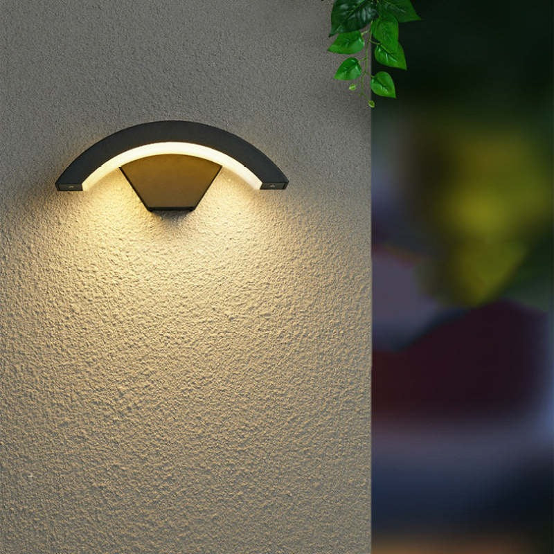 Arc outdoor wall light glowing warm on a textured rendered wall