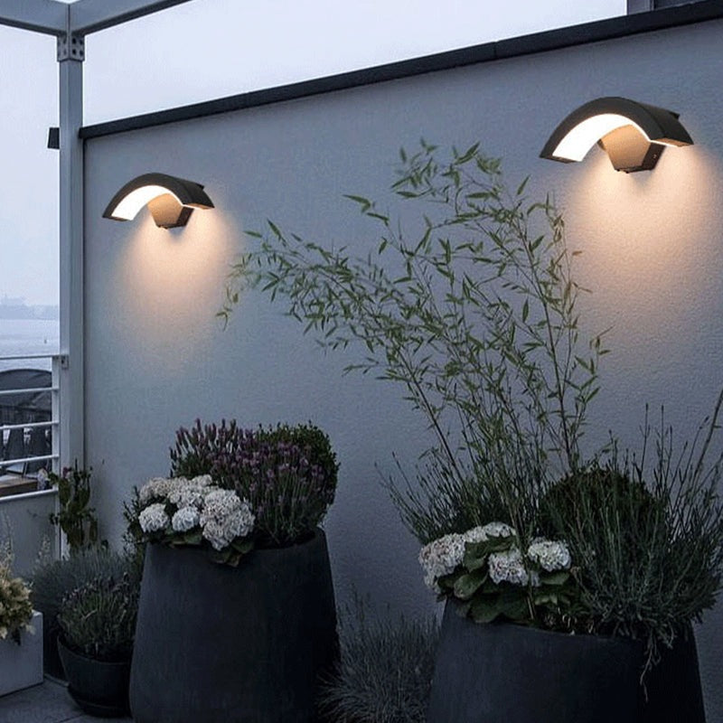 Arc outdoor wall lights on a courtyard wall above planters