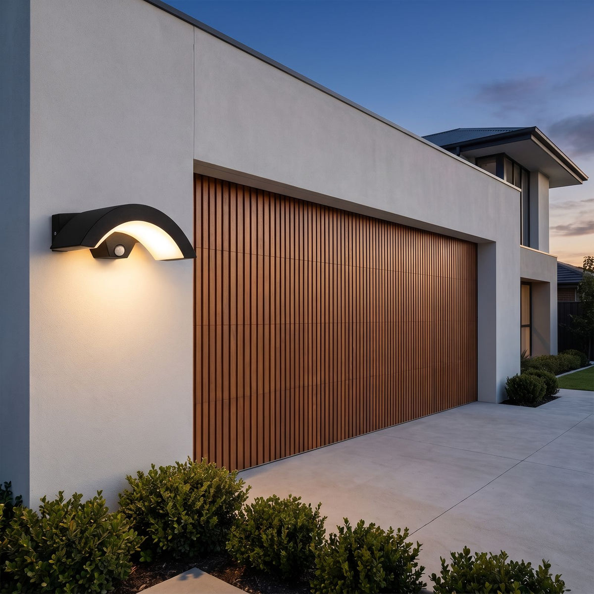 Arc Motion Sensor Outdoor Wall Light beside a timber garage door at dusk