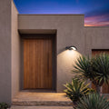 Arc Motion Sensor Outdoor Wall Light beside the oak front door of a contemporary rendered home at dusk