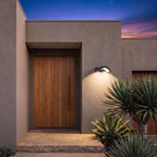 Arc Motion Sensor Outdoor Wall Light beside the oak front door of a contemporary rendered home at dusk