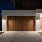 Two Arc Motion Sensor Outdoor Wall Lights either side of a timber batten garage door at night