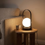 Arch frame frosted glass globe table lamp on a side table beside a sofa