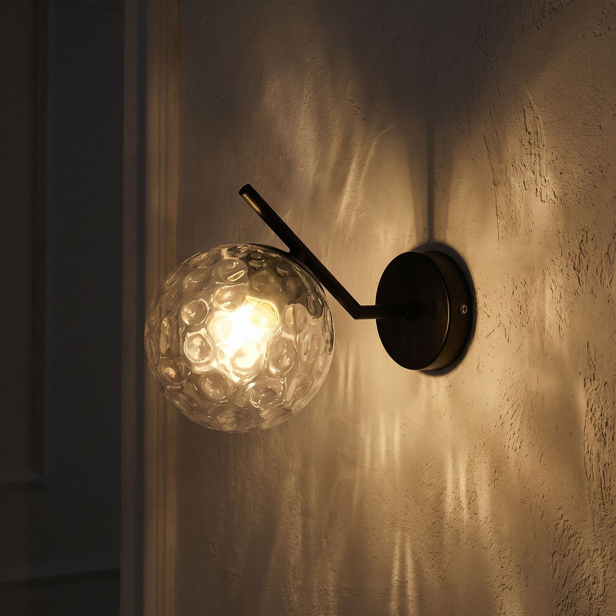 Art Deco Glass Ball Up Down Wall Sconce glowing on a plaster wall at night