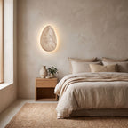 Backlit Floating Pebble Marble Wall Light on a bedroom wall beside the bed