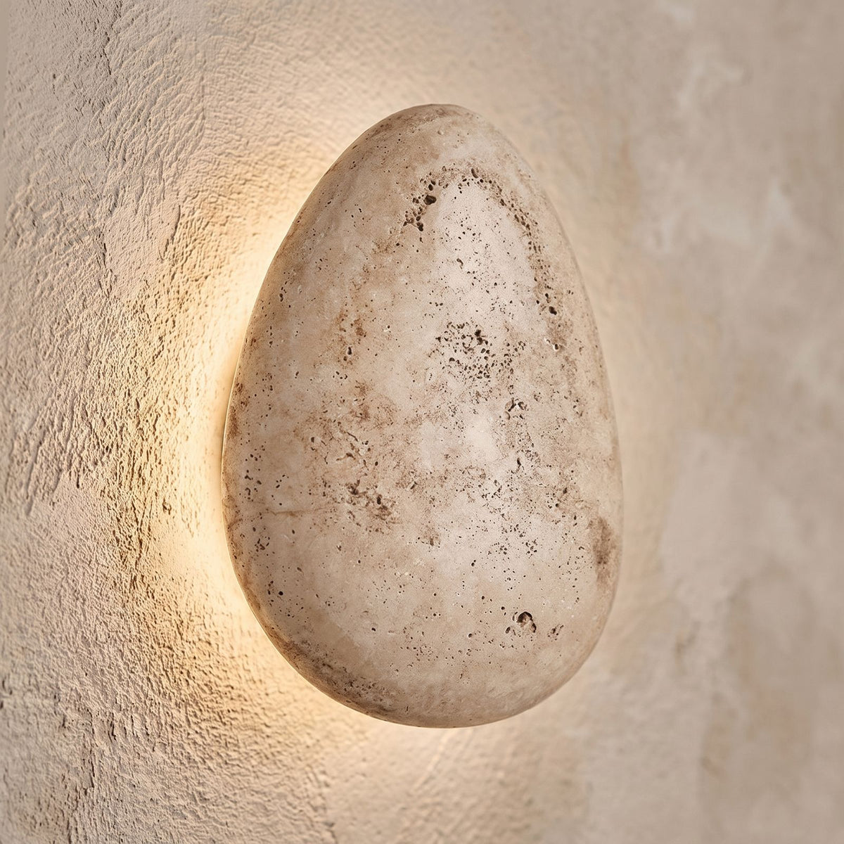 Backlit Floating Pebble Marble Wall Light, close view at 45 degrees on a plaster wall