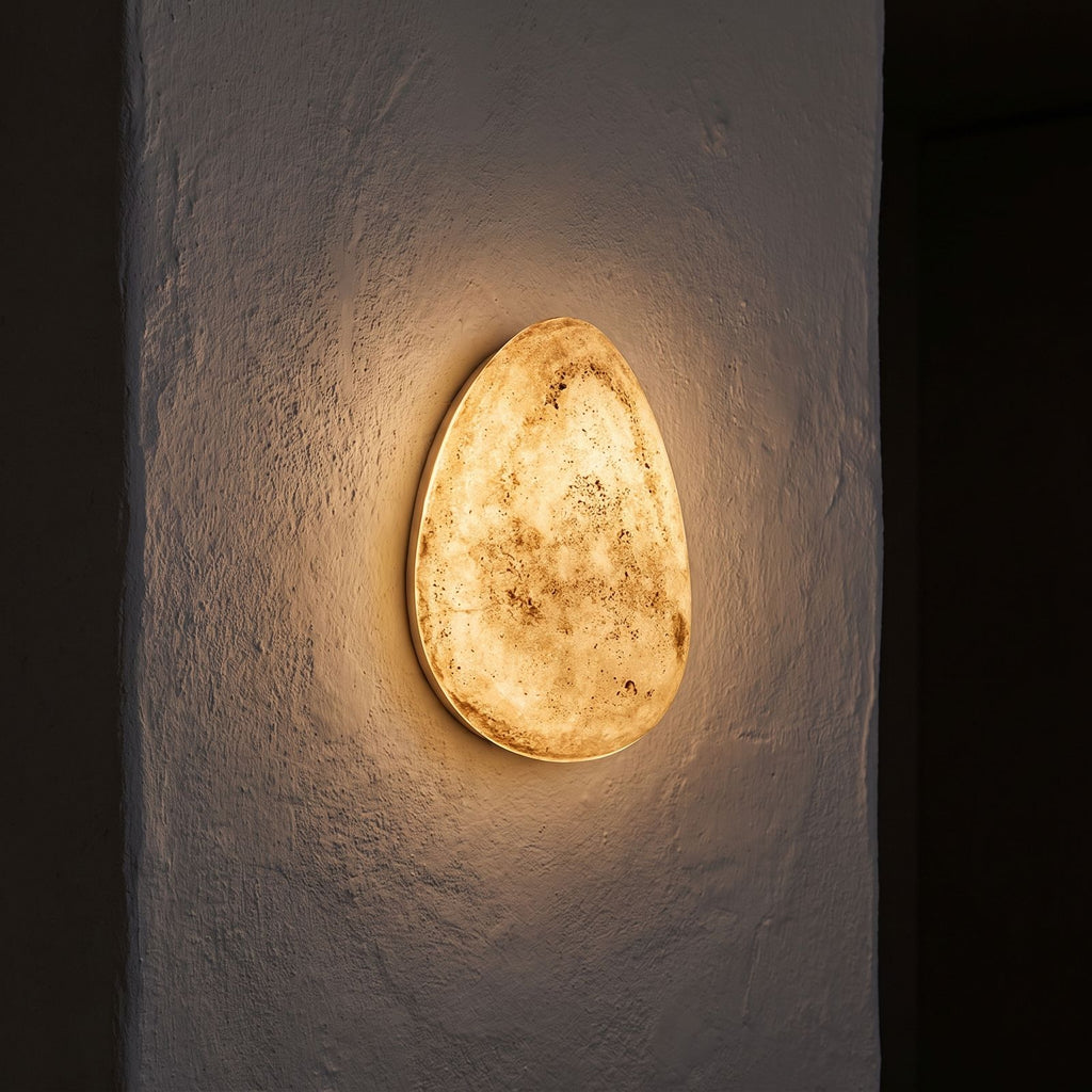 Backlit Floating Pebble Marble Wall Light glowing on a plaster wall at night