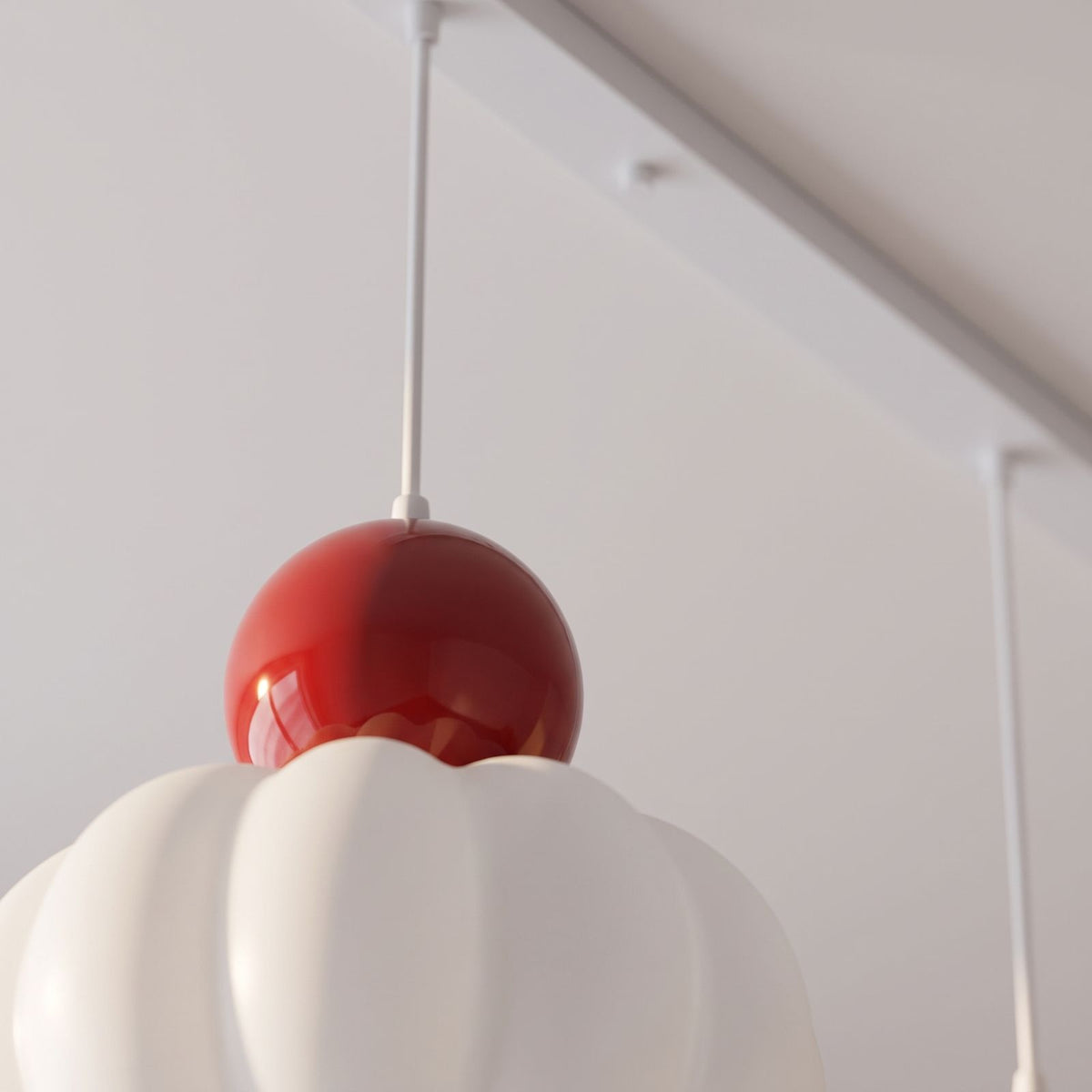 Close-up of the red ball top, cable and ceiling bar of the ball-top scalloped acrylic pendant