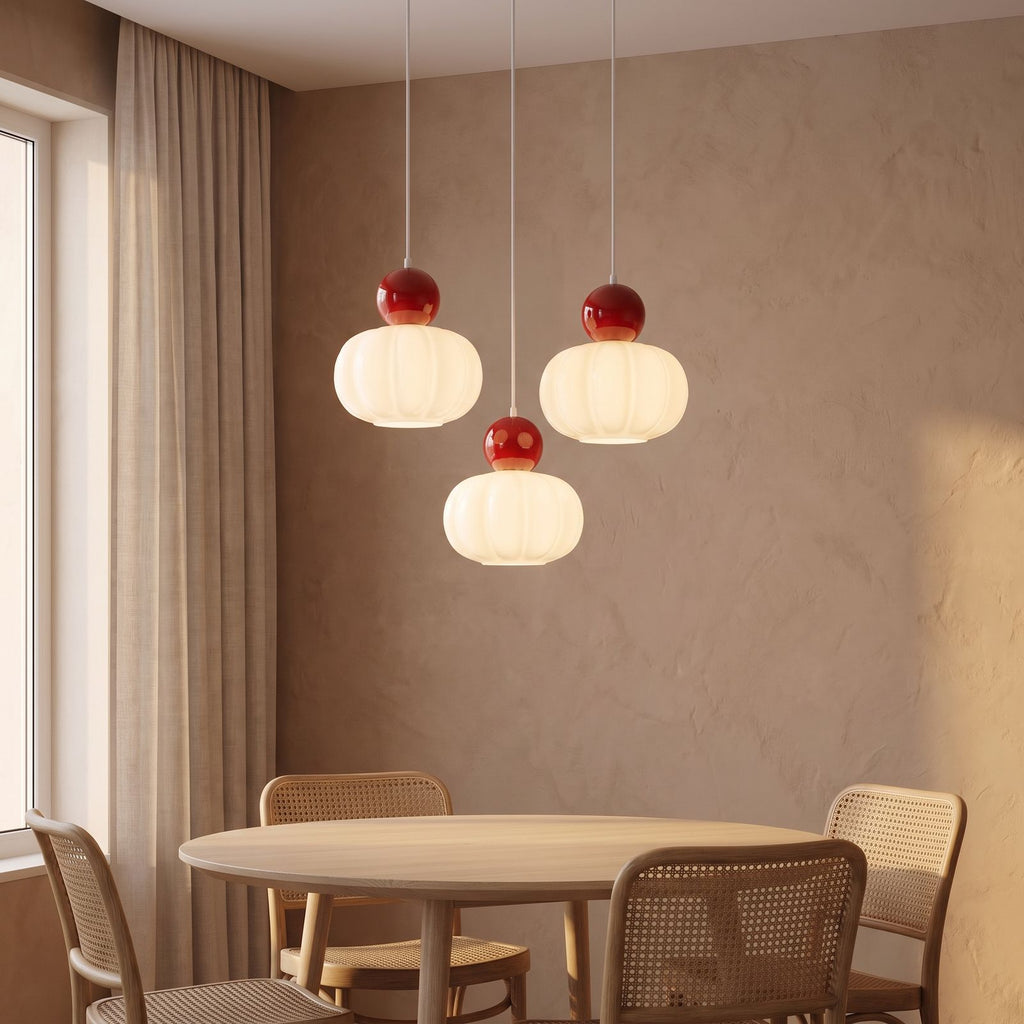 Ball-top scalloped acrylic 3-light pendant above a round dining table with the centre shade hung lower