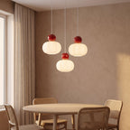 Ball-top scalloped acrylic 3-light pendant above a round dining table with the centre shade hung lower