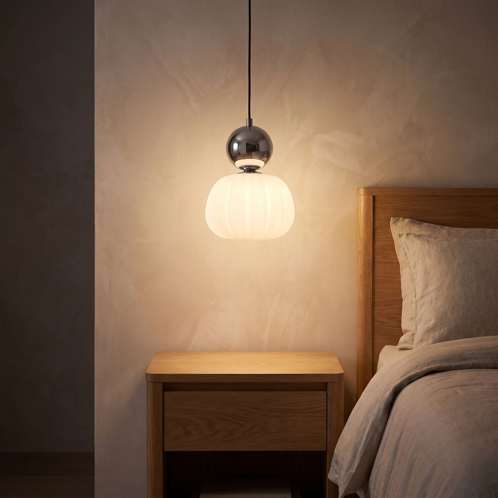 Ball-top scalloped acrylic pendant light over a bedside table at night