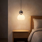 Ball-top scalloped acrylic pendant light over a bedside table at night