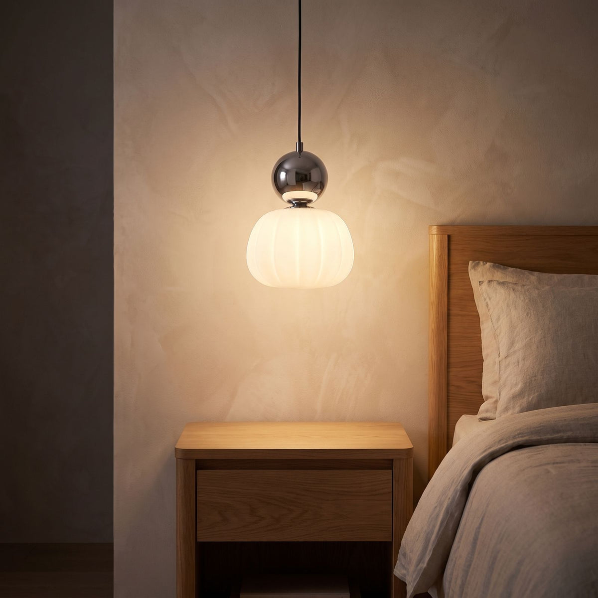 Ball-top scalloped acrylic pendant light over a bedside table at night