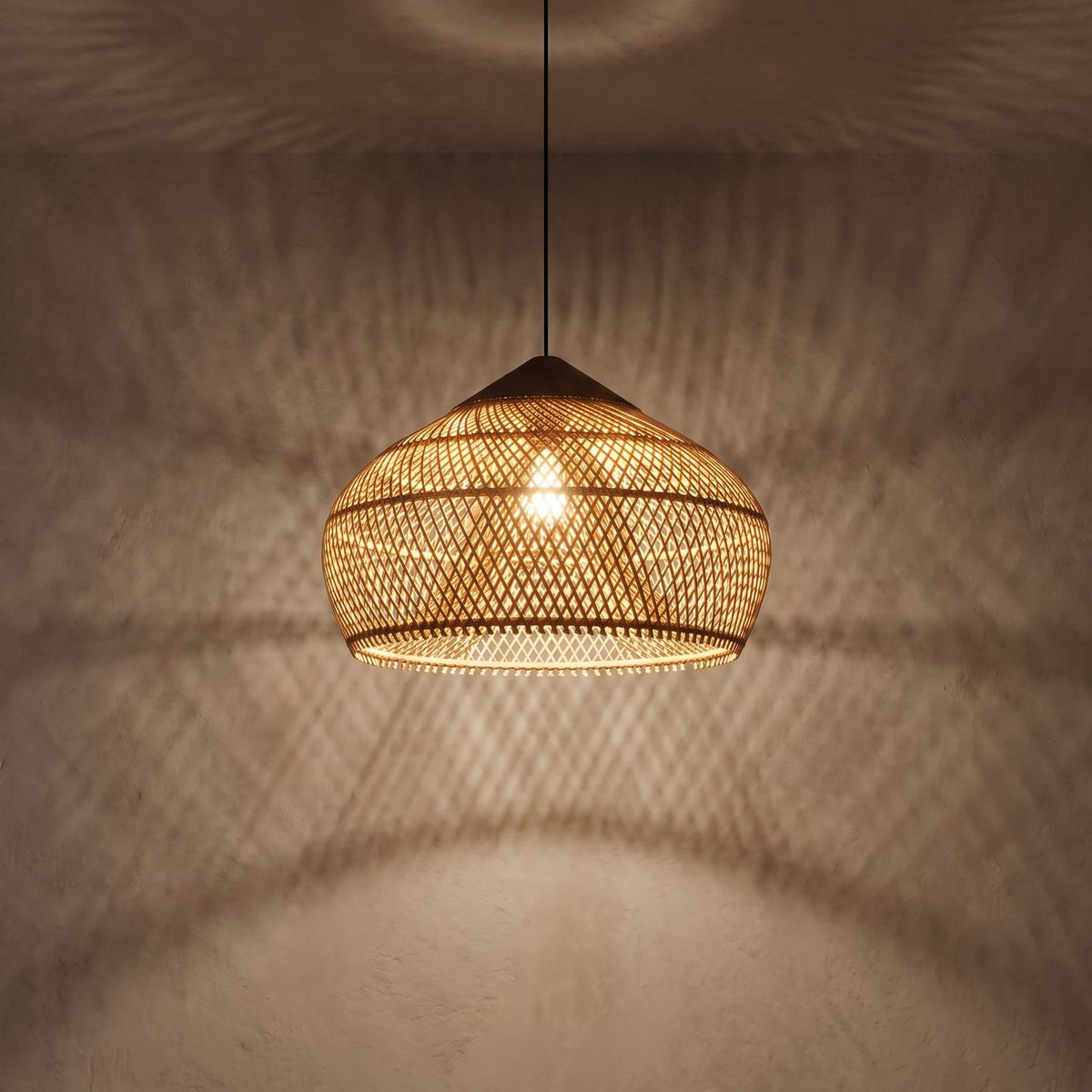 Bamboo Rattan Dome Pendant Light glowing against a plaster wall at night