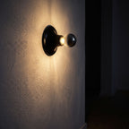 Bauhaus Retro Iron Wall Light glowing on a plaster wall at night