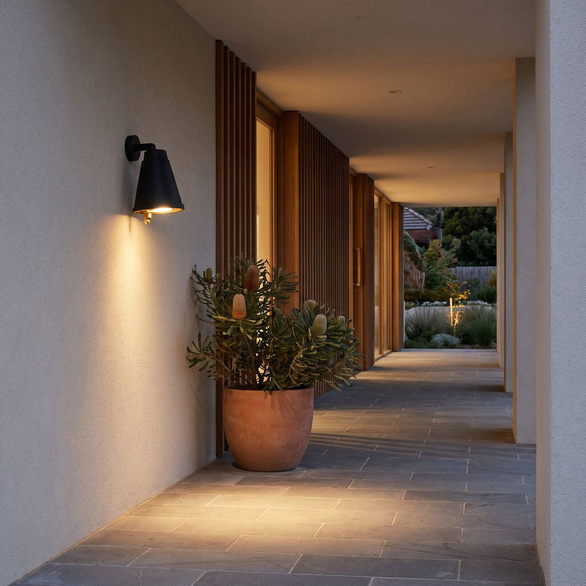 Bell Shade Aluminium Outdoor Wall Light on a rendered wall along a covered side walkway